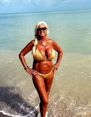 Mamie de plage blonde bronzée avec d'énormes faux seins